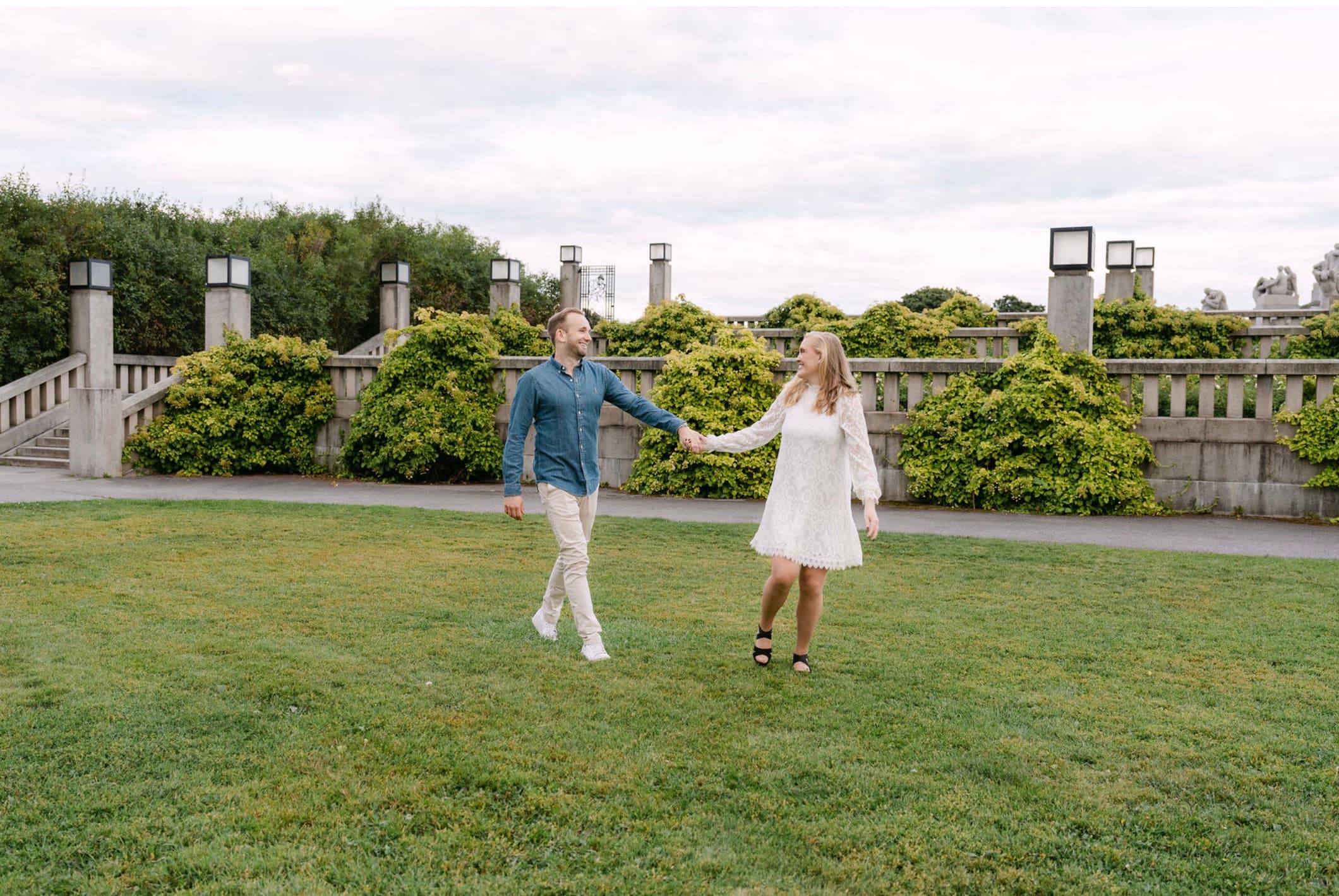Vilde og Marius går hånd i hånd over en plen i parken